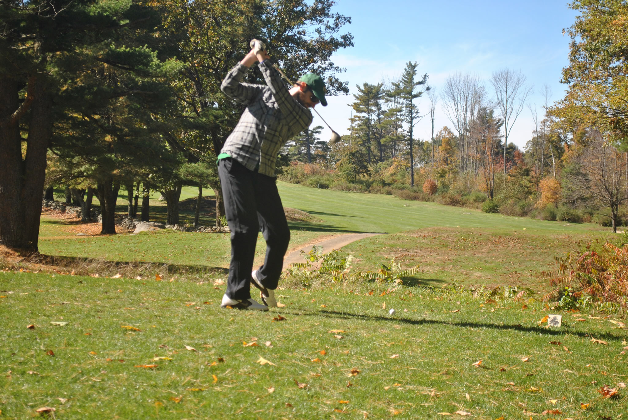 golfer swinging a club on a beautiful fall day