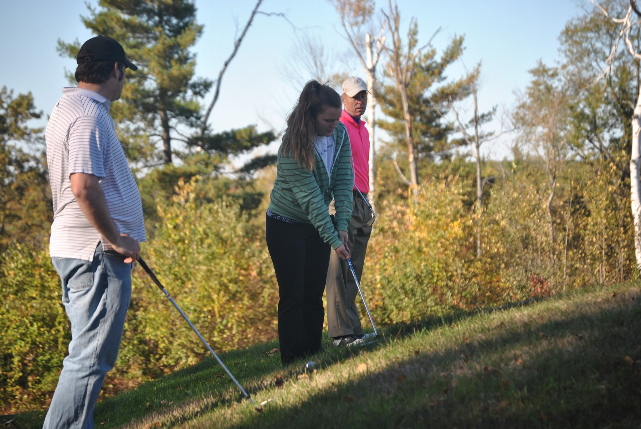 golfer putting with two other players on the course